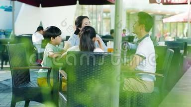 亚洲家庭在户外座位上喝酒和交谈，享受家庭欢乐时光，慢动作